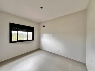 Uma sala de estar com paredes brancas e piso claro.
