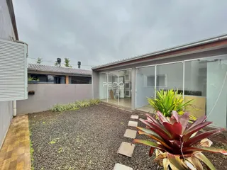 Vista externa de uma residência moderna em Lajeado, Brasil, com jardim e área pavimentada.