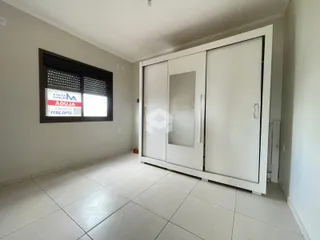 Interior de uma sala com piso de cerâmica e um armário embutido branco.
