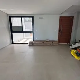 Sala de estar ampla com piso claro e porta de vidro no final do ambiente.