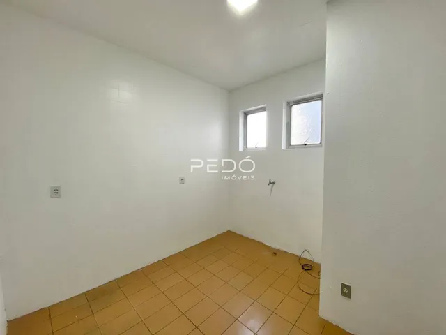 Interior de uma sala com paredes brancas e piso de cerâmica.