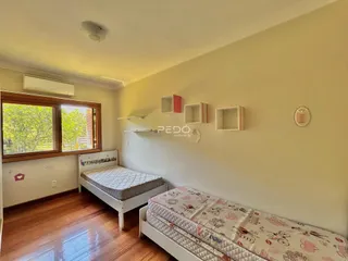 Quarto com duas camas e piso de madeira em um imóvel no Brasil.