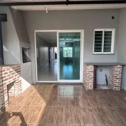 Sala de estar com piso de cerâmica e lareira de tijolos visível.