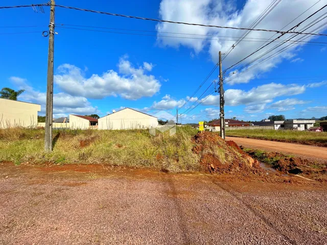 Vista externa de uma propriedade com terreno e vegetação ao fundo.