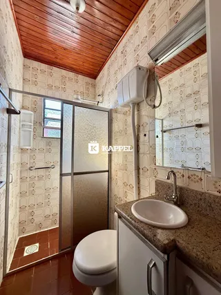 Banheiro com revestimento de azulejos brancos e teto de madeira aparente.