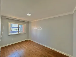 Uma sala de estar com piso de madeira e janela.