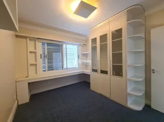 Sala de estar com armários brancos e janela.