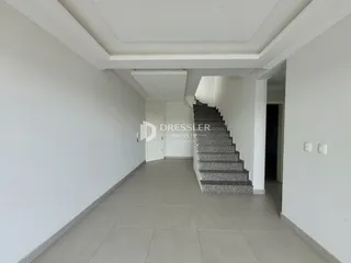 Corredor interno com escadaria e paredes brancas.