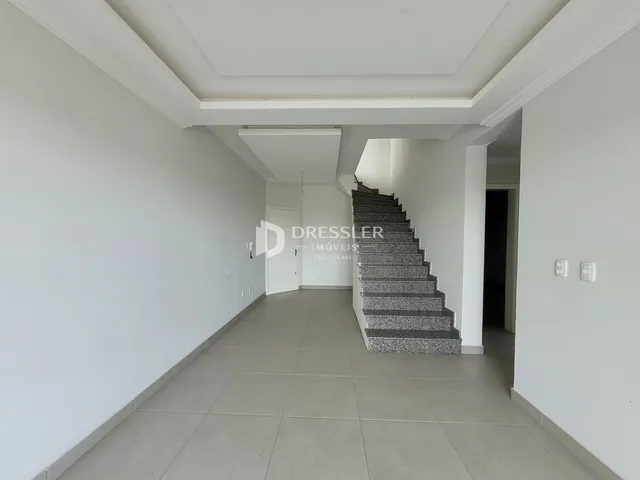 Corredor interno com escadaria e paredes brancas.