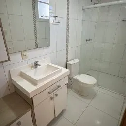 Banheiro interno com revestimento de azulejos brancos e pia.