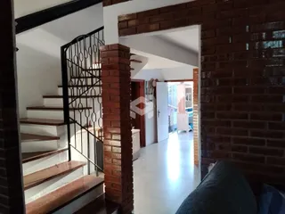Vista de um corredor interno com escadaria de metal e paredes de tijolo aparente.