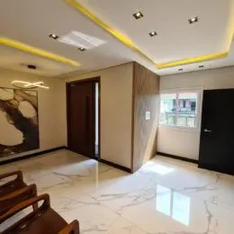 Sala de estar com piso de mármore claro e iluminação embutida.