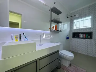 Banheiro moderno com bancada branca e revestimento texturizado.