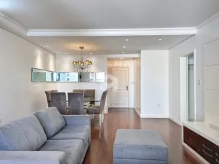 Sala de estar moderna com piso de madeira e móveis de couro.