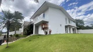 Fachada de uma casa moderna branca com jardim gramado em Lajeado.