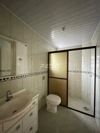 Um banheiro com azulejos brancos e box de vidro.