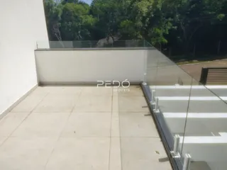 Vista de uma varanda com piso de cerâmica e guarda-corpo de vidro.
