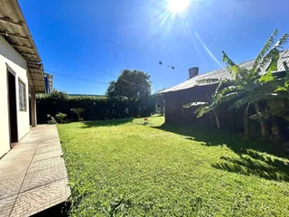 Vista externa da propriedade com um gramado verde e vegetação.