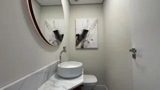 Banheiro com bancada de mármore, pia branca e vaso sanitário.