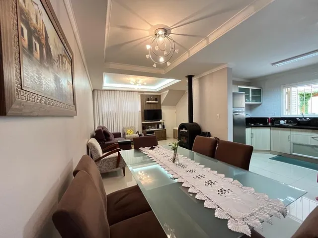 Sala de jantar com mesa de vidro e estofados em ambiente interno.