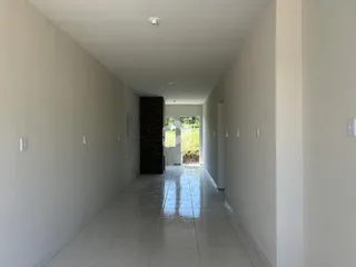Corredor longo com paredes brancas e piso de cerâmica refletivo.