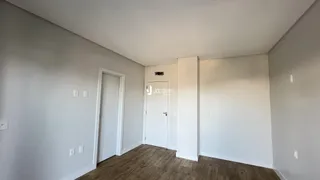 Hall de entrada com piso de madeira e porta branca.