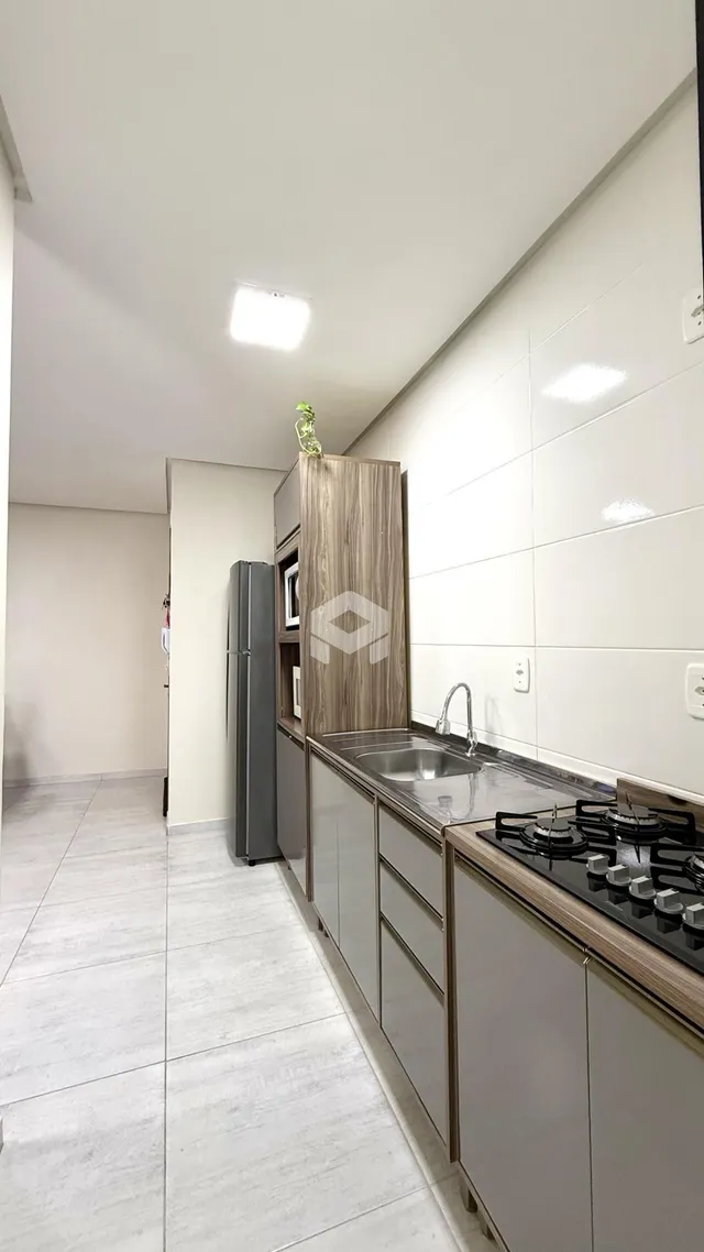 Vista interna de uma cozinha moderna com armários e revestimentos claros.