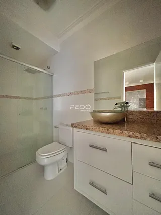 Foto de um banheiro com revestimento cerâmico e armário branco.