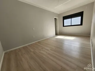 Foto de uma sala ampla com piso de madeira clara e janela.