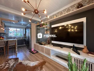 Sala de estar com piso de madeira e televisão montada na parede.