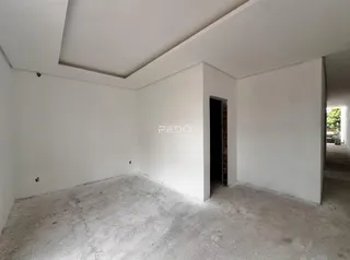 Interior de um cômodo com paredes brancas e piso de concreto cru.