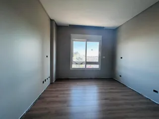 Um ambiente interno com paredes cinzas e piso de madeira.