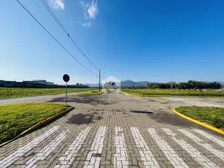 Vista aérea de uma área pavimentada com gramado e paisagem ao fundo.