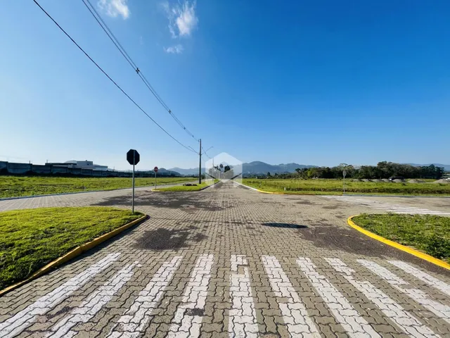 Vista aérea de uma área pavimentada com gramado e paisagem ao fundo.