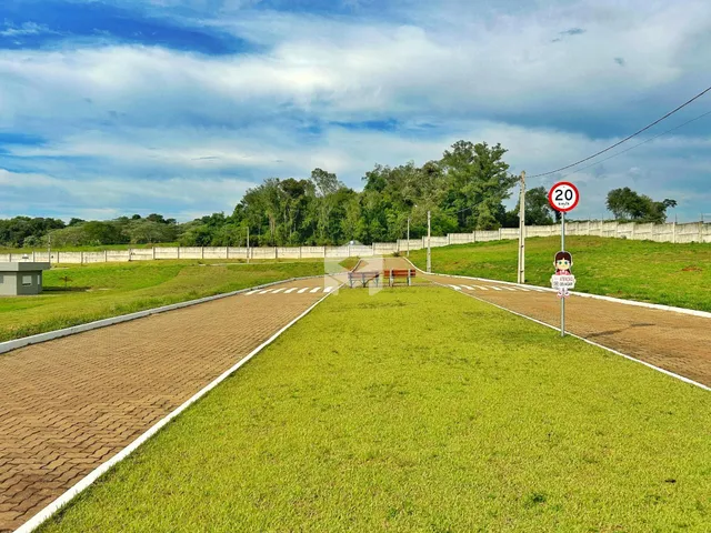 Vista da propriedade com gramado e cerca ao lado de uma estrada.