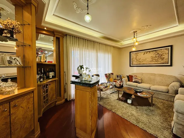 Sala de estar com decoração de madeira e cortinas brancas.