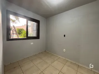 Vista interna de um cômodo com piso de cerâmica e janela.