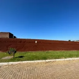 Paisagem de terra vermelha e grama verde sob um céu azul claro.