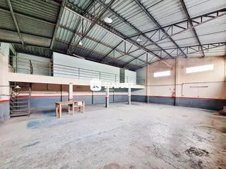 Espaço interno amplo com estrutura de telhado metálico e mezanino.