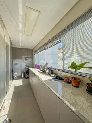 Vista da cozinha com bancada e janelas no imóvel.