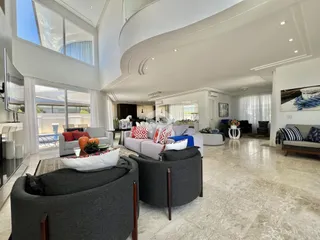 Sala de estar ampla com pé direito alto e portas de vidro que dão para o exterior.