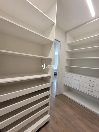 Interior de um ambiente com estantes brancas e armários brancos.