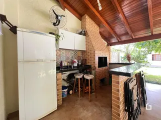 Vista da cozinha com armários brancos e parede de tijolos aparentes.