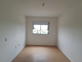 Vista interna de um cômodo com piso de madeira e janela.