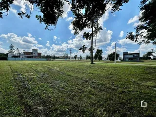 Campo gramado com árvores e edifícios ao fundo.