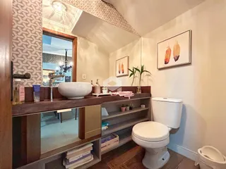 Foto de um banheiro com bancada de madeira e vaso sanitário branco.