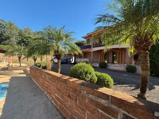 Fachada de uma residência em Lajeado, Brasil, com muro de tijolos e paisagismo.