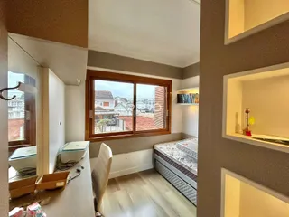 Quarto com janela de madeira e vista para a paisagem externa.