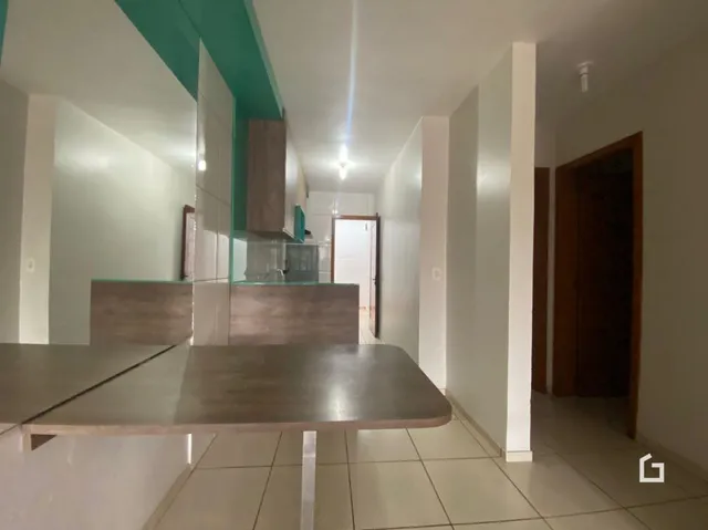 Vista interna de um corredor com paredes brancas e piso de cerâmica.