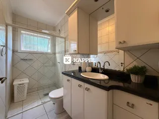 Foto de um banheiro com revestimento de azulejos brancos e bancada escura.